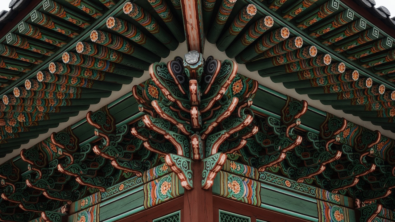 Bemalte Dancheong-Muster in Grün, Rot und Ocker an den Sparren und Konsolen des Gyeongbokgung-Palastes, Seoul
