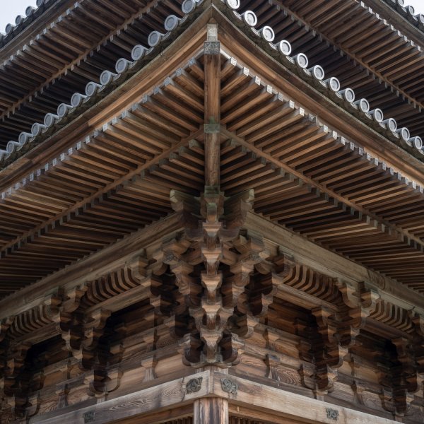 Ineinandergreifende Holzsparren und Verbindungen unter der Traufe eines japanischen buddhistischen Tempeldachs